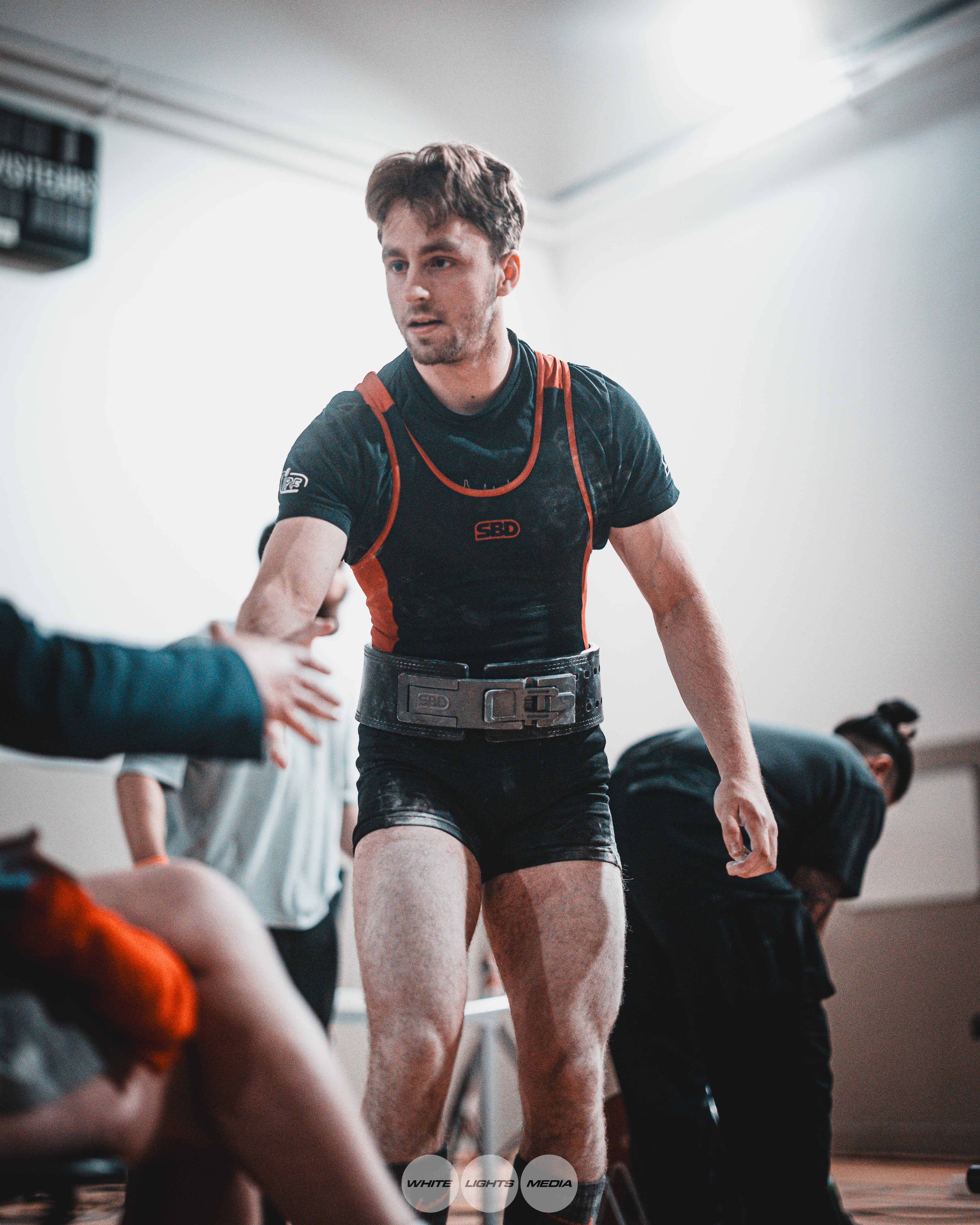 Antoine Fargeaud en compétition de powerlifting, combinaison avec bretelles oranges